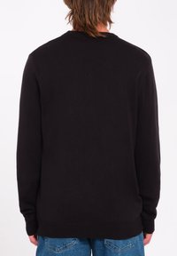 Maglione nero lavorato a maglia con scollo rotondo e maniche lunghe. Tessuto liscio, polsini e bordo a coste, design semplice. Vista posteriore soltanto.