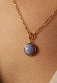 Collier en or avec un pendentif en pierre ronde de couleur violet pâle, au toucher lisse, entouré d'un fin cadre en or.