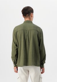 Olive green, textured long-sleeve shirt with a button-down collar and cuffs, featuring a center back pleat for ease of movement.