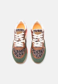 Une paire de baskets multicolores avec un imprimé léopard, des lacets blancs, du suède vert, des accents en cuir brun et une doublure intérieure orange vue de dessus.