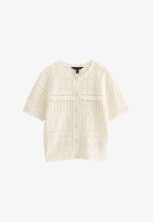 Cárdigan corto de punto color crema con mangas cortas, cierre frontal con botones y patrones de encaje intrincados por todo el tejido.