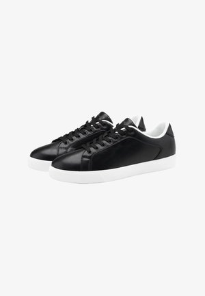 Černé kožené tenisky s hladkým povrchem, bílé gumové podrážky, kulatou špičkou a černými tkaničkami. Obsahují polstrovaný bílý límec a jazyk.