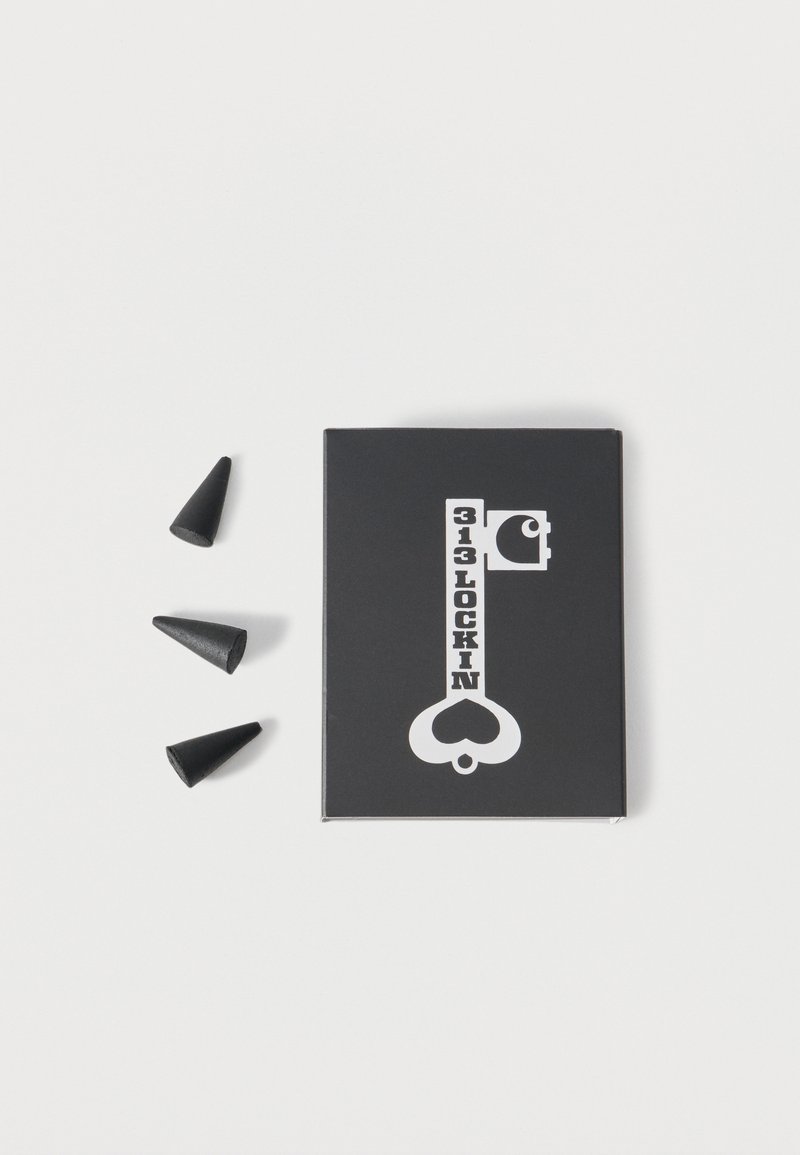 Μαύρο κουτί με λευκό γράφημα πλήκτρου που φέρει την ετικέτα "313 Lockin" δίπλα σε τρία μικρά μαύρα κωνικά αντικείμενα σε λευκό φόντο.