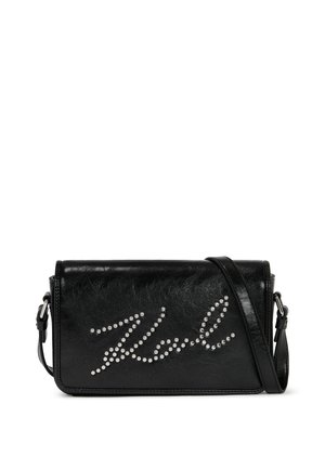 Sac en bandoulière en cuir synthétique noir avec un design en script clouté argenté. Forme rectangulaire avec une bandoulière amovible.