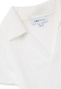 Witte textuur blouse met een kraag-halslijn, met een subtiel kreukelontwerp. Etiket leest "B ♥ ANGEL," maat S, met zorginstructies zichtbaar.