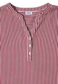 Chemise à rayures verticales rouges et blanches avec un col en V et trois boutons blancs sur le devant, étiquetée "CECIL" à l'intérieur du col.