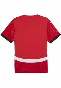 Rød træningsshirt med korte ærmer, der har et mønstret design på skuldrene og en hvid stribe ved nederste kant.
