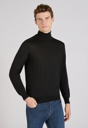 Schwarzer Rollkragenpullover aus feinem Strickmaterial, mit langen Ärmeln und taillierter Passform, kombiniert mit Jeans.