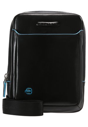 Bolso de cuero negro con detalles en azul, forma rectangular, cierre de cremallera, correa ajustable, con un logo en la parte inferior derecha. Textura suave.