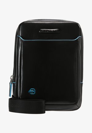 Schwarze Ledertasche mit blauen Akzenten, rechteckige Form, Reißverschluss, verstellbarer Tragriemen, mit einem Logo unten rechts. Glatte Textur.