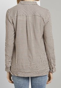 Chemise à carreaux marron et crème avec un col boutonné, manches longues et taille ajustée. Texture lisse avec un design décontracté.