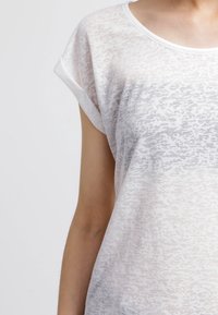 Vit kortärmad skjorta gjord av lätt, genomskinlig tyg med ett subtilt djurmönster och rund halsringning.