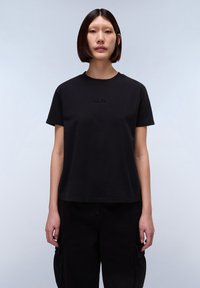 Černé bavlněné tričko s kulatým výstřihem, krátkými rukávy a texturovaným logem "NAPA" na hrudi. Spárováno s černými cargo kalhotami.