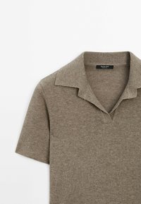 Polo en maille à manches courtes couleur taupe, en tissu texturé avec col ouvert, doté d'une étiquette de marque à l'intérieur du col.