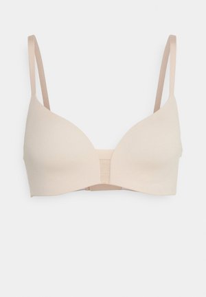 Beige bra with smooth, seamless cups, adjustable straps, and an elastic band in the center for support. Simple design, no additional embellishments.
