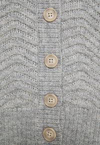 Jasnoszary dziergany kardigan o falistej fakturze, z czterema kremowymi guzikami z przodu i prążkowanymi mankietami.