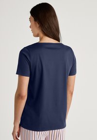 Donkerblauwe T-shirt met korte mouwen en een ronde halslijn, met een zachte textuur en zijsplitten, gecombineerd met gestreepte pyjamabroek.