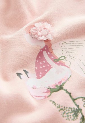 Hellrosa Stoff mit floralem Muster, das eine Figur zeigt, die mit einer pinken Blume geschmückt ist. Der Stoff hat eine weiche Textur und gepunktete Akzente.