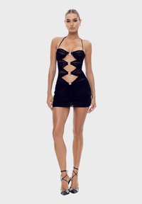 Zwarte mini-jurk met een aansluitend ontwerp, voorzien van uitsneden en metalen accenten. Gemaakt van een soepele, rekbare stof die het lichaam mooi vormt.
