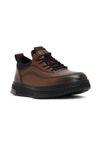 Chaussures en cuir marron avec une finition lisse, accents noirs, design à lacets et semelle en caoutchouc noir texturée avec un motif en maille.