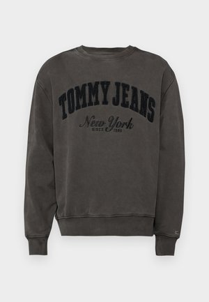 Sivi dukserica s okruglim izrezom i rebrastim manžetama. Na prednjoj strani se nalazi veliki, baršunasti crni logo s natpisom "TOMMY JEANS New York".