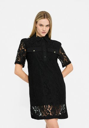 Schwarzes Spitzenkleid mit kurzen Ärmeln, kragenlosem Hals, Knopfleiste und zwei aufgesetzten Taschen. Mit floralem Spitzenmuster und gewelltem Saum.