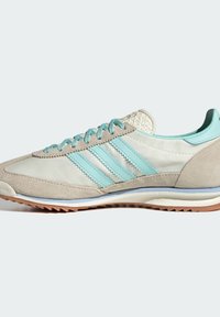 Chaussures de sport beiges et bleu clair, présentant des matériaux en suède et en cuir lisse, trois rayures texturées et une semelle en caoutchouc avec un léger motif de traction.