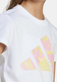 T-shirt bianca in cotone con una grafica floreale multicolore nei toni del rosa e del giallo, con collo rotondo e maniche corte.