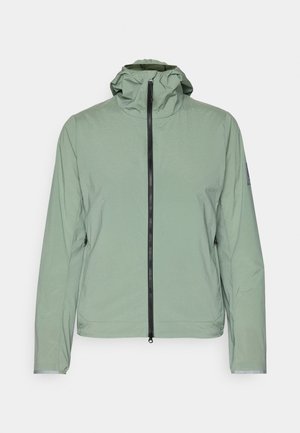 Lysegrønn, lett jakke med glidelås, justerbar hette og elastiske mansjetter. Har en enkel, glatt tekstur og minimalistisk design.