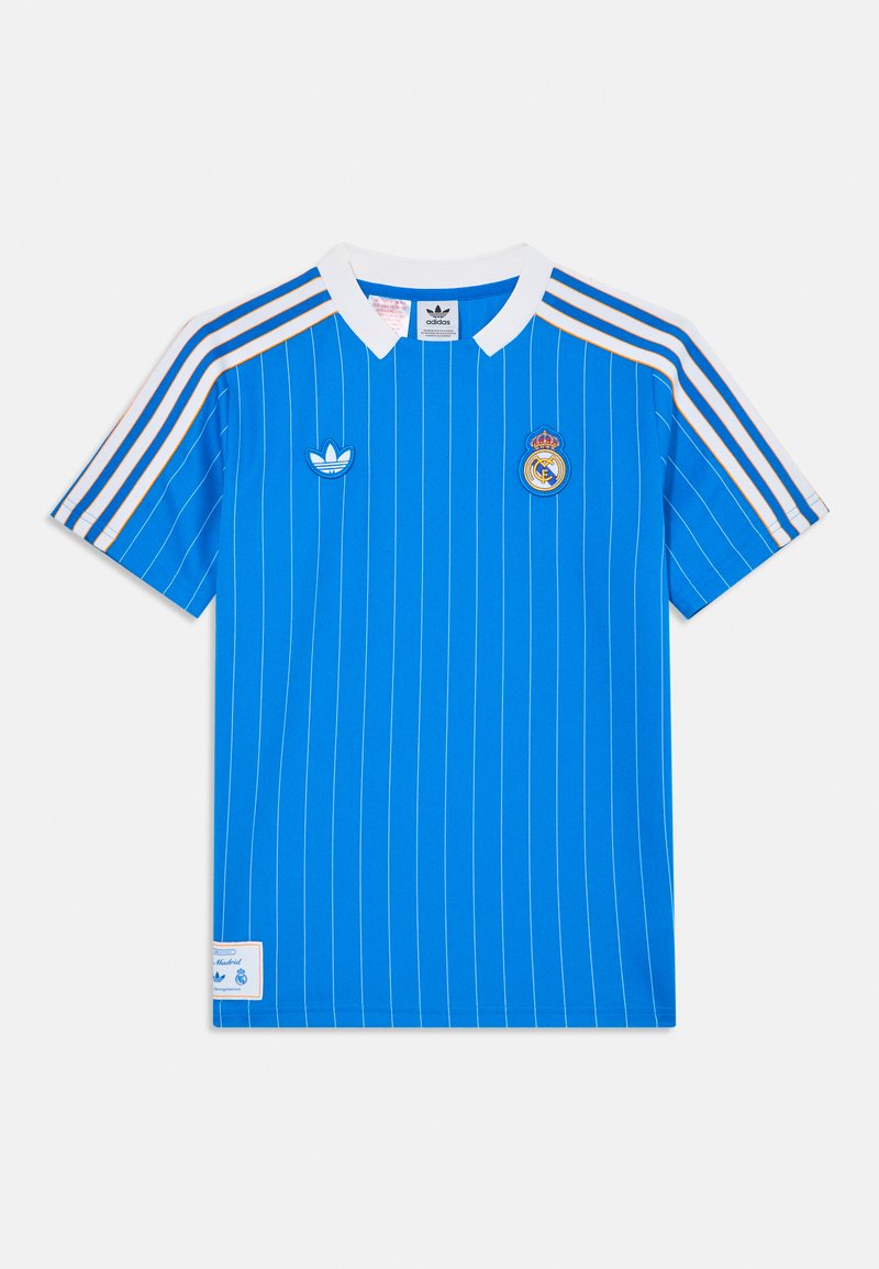Maillot Adidas du Real Madrid en bleu vif avec des rayures blanches horizontales. Il présente un col blanc, un logo sur la poitrine et trois rayures sur les épaules.