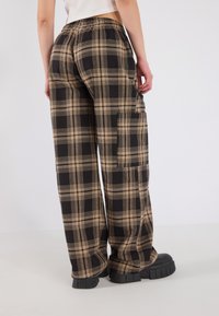 Zwarte enbruine geruite wijde broek met een elastische tailleband, met een relaxte pasvorm en subtiele textuur.