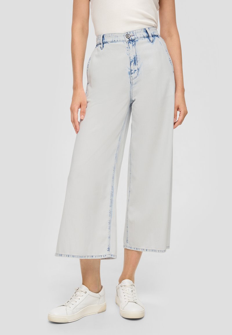 Jasnoszare dżinsy o szerokich nogawkach, wykonane z denimu, z efektem przetarcia wzdłuż krawędzi. Posiadają zapięcie na guzik oraz głębokie kieszenie z przodu.