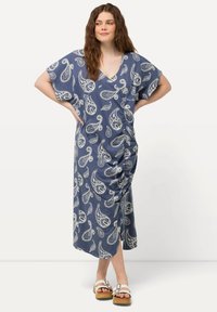 Tummansininen maksimekko, jossa on paisley-kuvio, lyhyet hihat ja V-pääntie. Yhdessä sivussa on rypytys, ja se on valmistettu kevyestä kankaasta.