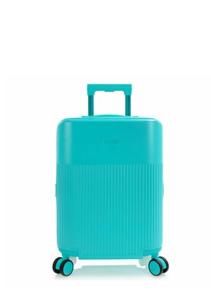 Maleta rígida color azul verdoso con relieves verticales, asa telescópica y cuatro ruedas dobles giratorias sobre fondo blanco.