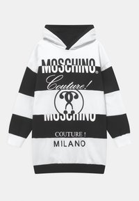 Mikina s kapucí černobílými vodorovnými pruhy, se silnými logy "Moschino Couture" a velkým kruhovým designem uprostřed.