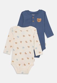 Due bodysuit per neonati: uno crema con stampa di orsetti e uno blu a costine con una toppa a forma di orso e bottoni di legno. Tessuto in cotone morbido.