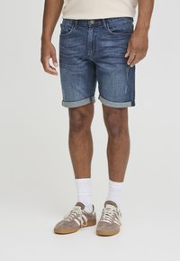 Shorts en denim bleu foncé avec un ourlet retroussé, comportant cinq poches, des coutures contrastantes et des détails usés sur le devant.