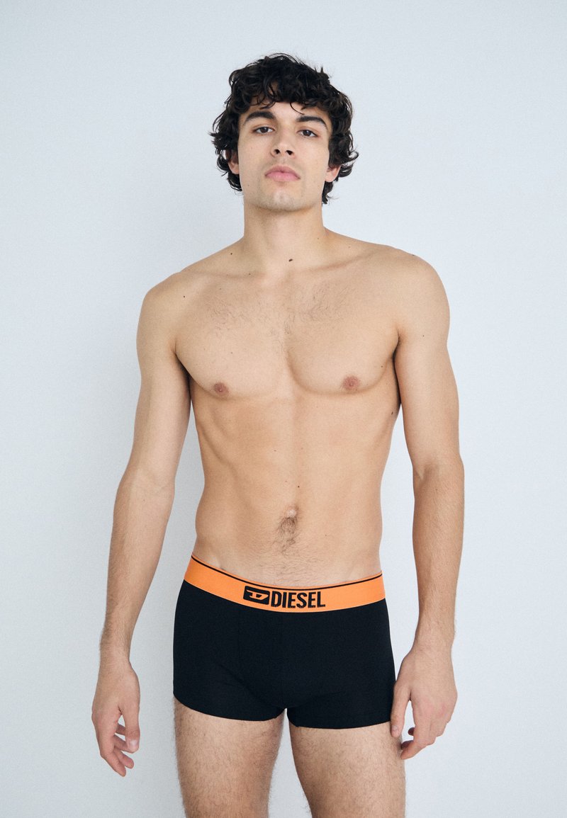 Caleçons boxers noirs avec une taille en logo orange de Diesel. Le tissu paraît lisse, et le design est ajusté avec une forme simple.