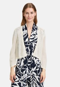 Gehaakte lichte cardigan in crème, met een korte, open voorkant, lange mouwen en een gestructureerde, ademende stof.