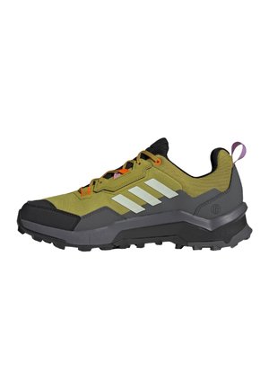 Zapatilla de trail running en verde y negro con una parte superior de tela texturizada, acentos reflectantes y una suela de goma resistente. Cuenta con cordones naranjas.