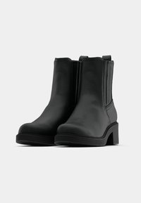 Mustad nahast pahkluu saapad, sileda tekstuuriga, elastsete külgpaneelide, madalate plokk-kontsade ja minimalistliku disainiga.