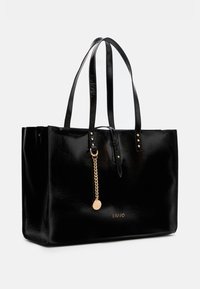 Borsa a spalla nera in pelle sintetica con manici lunghi, finitura lucida e dettagli in oro. Presenta una catena decorativa con un ciondolo con logo.
