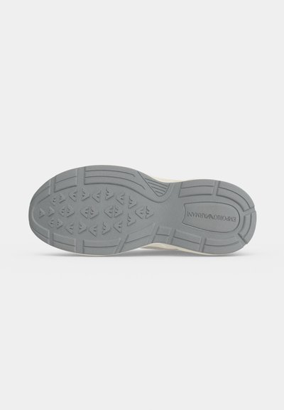 Semelle de chaussure avec motif de bande de roulement gris comprenant des formes triangulaires et le logo "EMPORIO ARMANI" près du talon sur fond blanc.