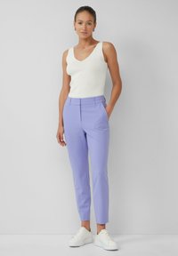 Helllila maßgeschneiderte Hose mit glatter Textur, ausgestattet mit einem flachen Bund und seitlichen Taschen, kombiniert mit einem weißen, eng anliegenden Top.