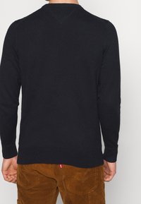 Maglione di un blu navy scuro realizzato in morbido tessuto a maglia, con scollatura tonda classica, maniche lunghe e orlo a coste. Design semplice, senza motivi.