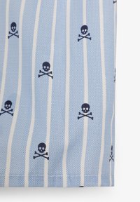 Tela azul claro con rayas blancas verticales, que presenta un patrón de calaveras y huesos cruzados en azul marino. Tejido texturizado con un acabado suave.