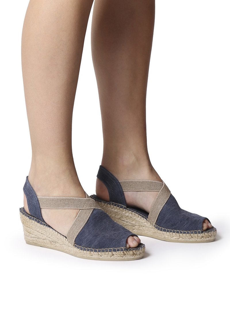 Sandalové wedge s otevřenou špičkou, které mají modrý textilní svršek se světlými akcenty a jutu v espadrilkovém stylu. Nastavitelné popruhy pro lepší přizpůsobení.