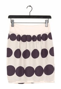 Jupe crème à grands pois violet foncé, avec une ceinture froncée. Suspendue à un cintre noir. Tissu lisse et design simple.