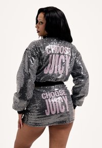 Szürke flitteres zakó és szoknya szett, amely hátul rózsaszín "CHOOSE JUICY" felirattal díszített. Az anyag fényes, és a fazon testhez simuló.