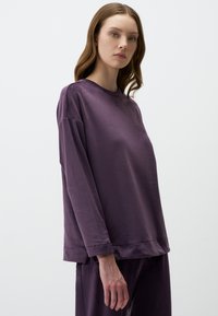 Maglia a maniche lunghe viola con una vestibilità comoda, realizzata in tessuto morbido e strutturato. Presenta un collo a giro e spalle scese.